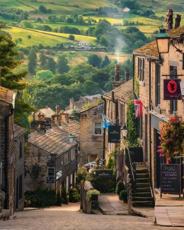 english countryside landscape at a distance seen from a sloped street in haworth, a village in west yorkshire, england.