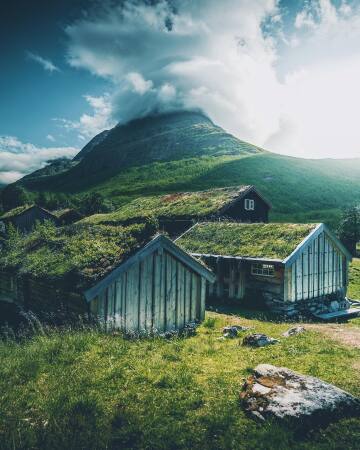 innerdalstårnet mountain seen behind the abandoned turf roof cabins in innerdalen valley, møre og romsdal county, western norway.
