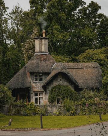 thatched roof cottage with a chimney in wiltshire, south west england.