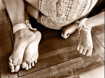 nice shot of hands tied behind back, with ankles tied as well