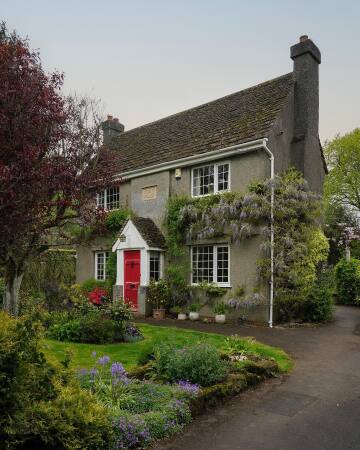 cottage with a bright red door in sandy lane, a tiny village in wiltshire, south west england.