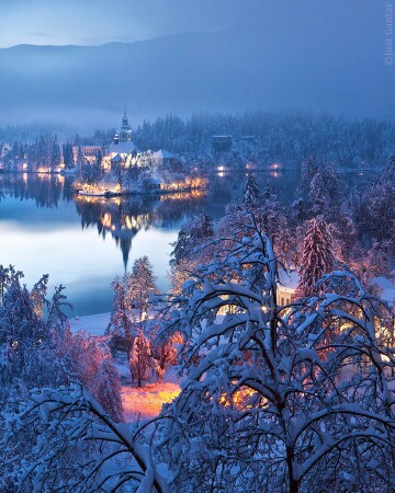 snow-covered shores of lake bled in the julian alps during a winter evening, upper carniola, northwestern slovenia.
