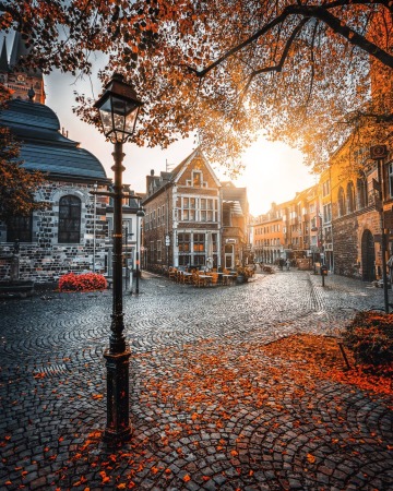 cobblestone street near aachen cathedral covered with fallen leaves, historic city of aachen, north rhine-westphalia, germany.