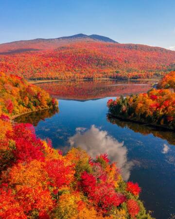 mountains covered with autumn foliage reflected in lake eden in the town of eden, lamoille county, vermont.