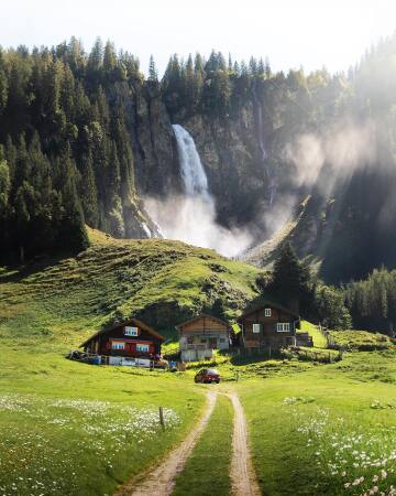 waterfall behind some wooden cottages in the canton of uri, central switzerland.