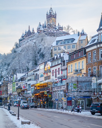 snow-covered cochem castle atop a hill overlooking the town of cochem, rhineland-palatinate, germany.