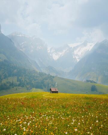 small house on a hillside with views of the distant mountains, appenzell, canton of appenzell innerrhoden, northeastern switzerland.