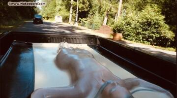 restrained in a vacbed on the flatbed of a truck and driven through town.